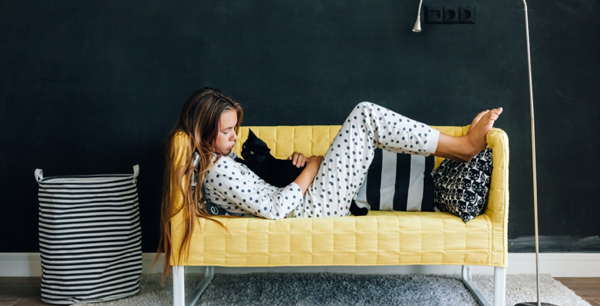 a girl comfortably on a couch with her cat